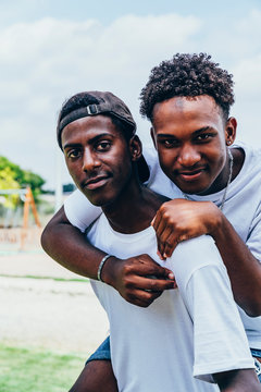 Cheerful hugging African American young men looking at camera and gesturing