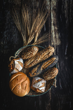 Gold assortment bread homemade on dark wood background, captured from above top view, flat lay in knolling concept