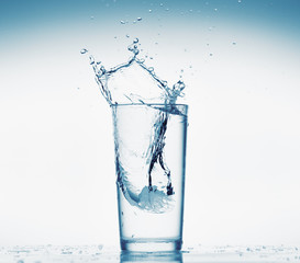 one glass of water with splash from falling ice cube, white background, isolated object
