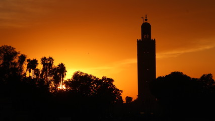 Panoramic view of the Orange Sunset in the tower of the Marrakech square from a terrace and the sun in the background. Morocco