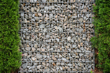 Close up of grid fence with stones and green trees