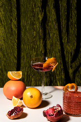 Various citrus fruits and pomegranate with fruity cocktails in front of a heavy green velvet carpet. Abstract conception.