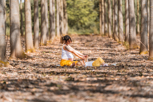 Pregnant mother and little daughter resting in park