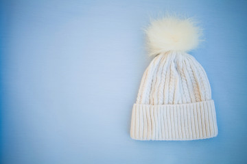 Fototapeta na wymiar White knitted hat on a blue background.