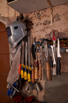 Set of work tools and protective clothes for welding and soldering hanging on old flake wall of workshop