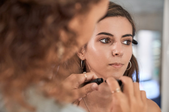 Concentrated makeup artist doing makeup on a beautiful woman client in a salon