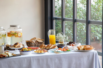 From above of appetizing sitting table for breakfast with bakery seafood sandwiches eggs and orange juice at stylish dinning room
