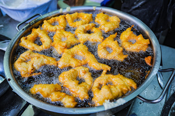 Deep fried traditional dessert in a boiling oil. Making a dessert. SFINGE fries deep in boiling oil. Junk food.