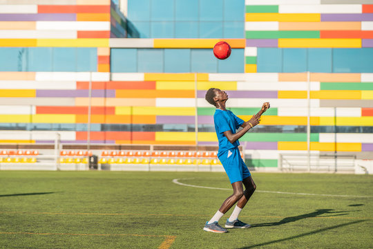 Skinny black teenager jugging football ball on head