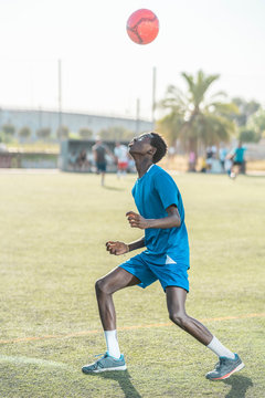Skinny black teenager jugging football ball on head