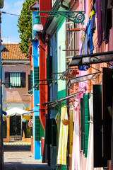 narrow alley without people with colorful houses and clothes hanging in Burano, Venice, Italy