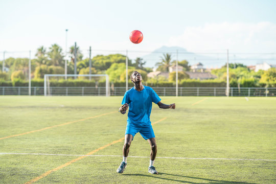 Skinny black teenager jugging football ball on head