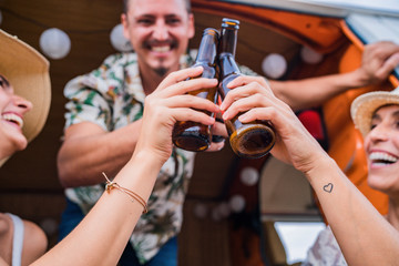 Smiling cheerful friends raising bottles of drink and clinking for holiday in car