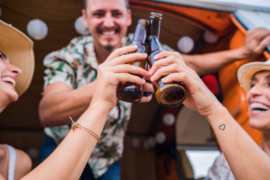 Smiling cheerful friends raising bottles of drink and clinking for holiday in car