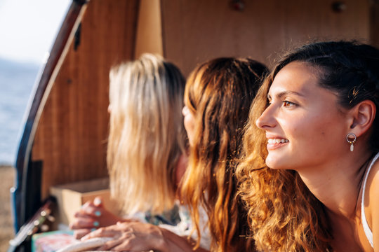 Pleasant ladies lying on trunk of bright minivan in sunny day
