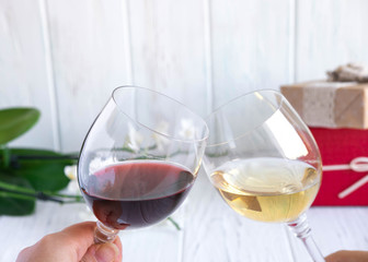 Two glasses with red and white wine on the background of gift boxes. Celebrating the new year, birthday, discounts and bonuses.