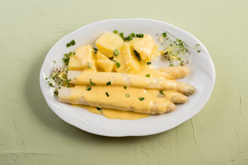 white asparagus poured with .hollandaise sauce, potatoes with chives and sprouts.