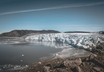Greenland, Eqip Sermia, Eqi Glacier in Greenland Disko Bay. Boat trip in the morning over the arctic sea,Baffin Bay, calving glacier. Ice breaking of on a blue sky wth clouds.