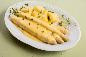 white asparagus poured with .hollandaise sauce, potatoes with chives and sprouts.