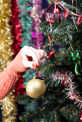Girl decorates a Christmas tree with a golden ball.