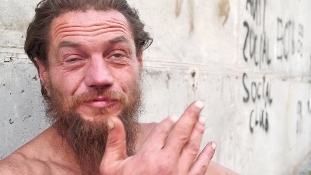 Destitute man looks at camera and talks, real person with no fixed abode. Homeless wanderer talks on camera