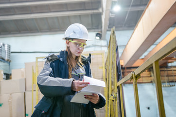Young female technician in uniform, protective eyeglasses and helmet