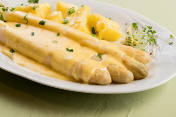 white asparagus poured with .hollandaise sauce, potatoes with chives and sprouts.