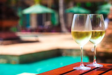 Elegant flute glass of sparkling white wine or champagne by side of swimming pool