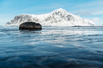 View of a landscape of a Norwegian fjord with a snowy mountain reflecting in the water. Norway, Lofoten Islands