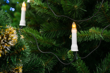 festive illumination on a festive tree. New Year holiday. Garland in the form of candles