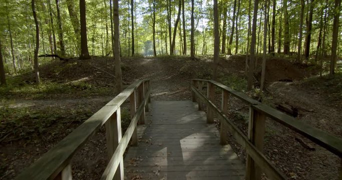 First person view walking along a wooden bridge on a forest trail