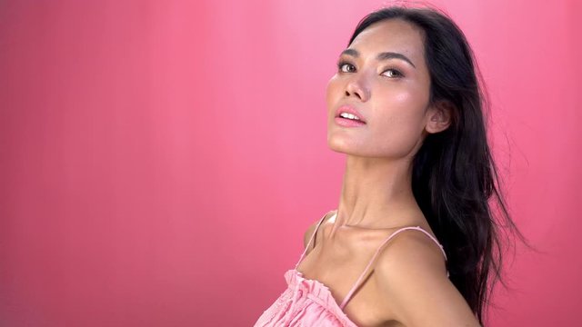 4K Portrait of happy young beautiful asian woman girl face and body with long hair wearing pink tops are smiling isolate pink background. Human face and body with happy relax emotion concept.