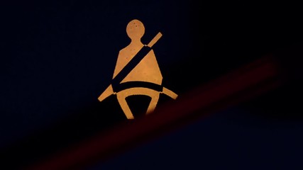 The yellow warning light flashes on the dashboard of the vehicle. Unfastened seat belt. Macro close up. - Powered by Adobe