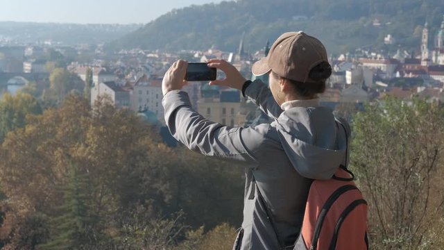 Photo of a top of Prague. Girl tourist photographs the cityscape of old Europe.