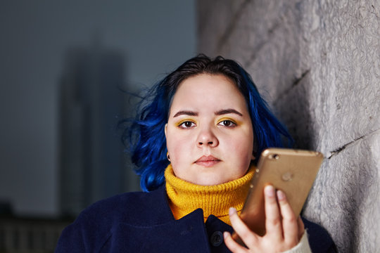 Attractive Teenager With Blue Hair Holds Smartphone.