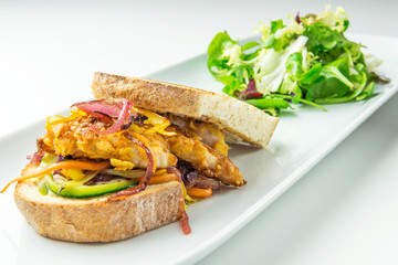 Breaded fish fillet sandwich with vegetables and mustard