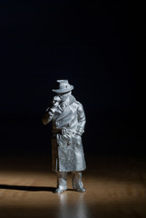 Man of the 1950s smoking a cigarette with raincoat and hat made in white metal