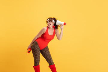 Fototapeta na wymiar Young caucasian plus size female model's training on yellow background. Copyspace. Concept of sport, healthy lifestyle, body positive, fashion, style. Stylish woman calling using mouthpeace.