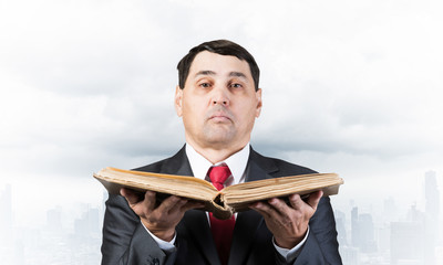 Serious businessman holding open old book