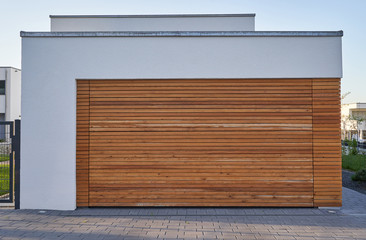 A modern Scandinavian-style garage with a wood-paneled garage door. Private garage with automatic door in a European city in Germany