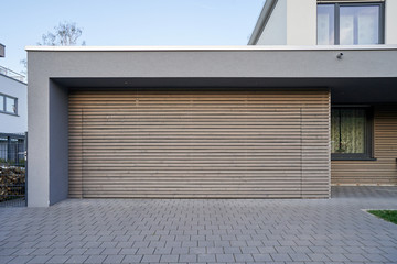 A modern Scandinavian-style garage with a wood-paneled garage door. Private garage with automatic door in a European city in Germany