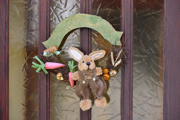 Entrance door to the house with decorations for Easter, a toy hare, branches and carrots and a place for text