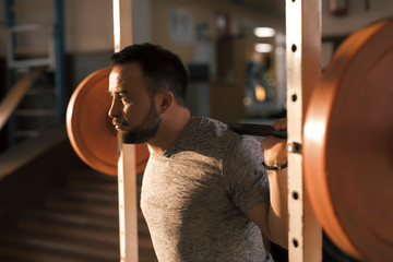Man squat with barbell in a fitness gym making his muscles more strong