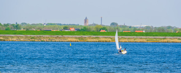 ship sailing on the oosterschelde with the city scenery in the background, Tholen, Zeeland, The netherlands