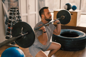 Man make front squat with barbell in a fitness gym making his legs muscles more strong