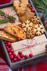 Homemade christmas cookies and wrapped presents with fresh cranberries in a wooden box