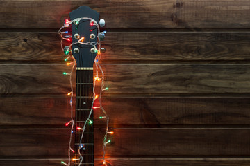 acoustic guitar fretboard in a New Year's garland, a guitar in a garland under a wooden wall, copy...
