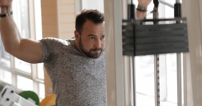 Man exercising in a gym making his muscles more stronger, healthy lifestyle concept, muscular build