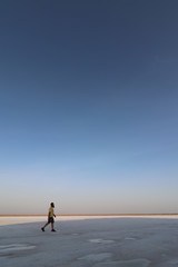 Man running through the desert/on a beach at sunset