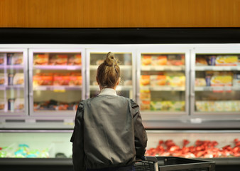 Woman choosing frozen food from a supermarket freezer	